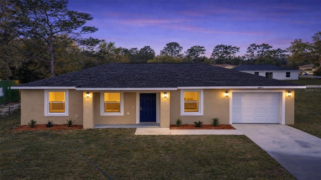 A single-story house with a beige stucco exterior, a blue front door, and a garage — 24763 NW HIGHVIEW AVENUE, DUNNELLON, FL