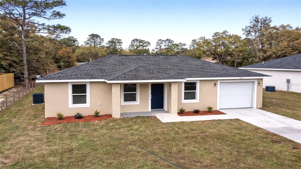The exterior of a single-story house features a blue front door and a covered porch — 24763 NW HIGHVIEW AVENUE, DUNNELLON, FL