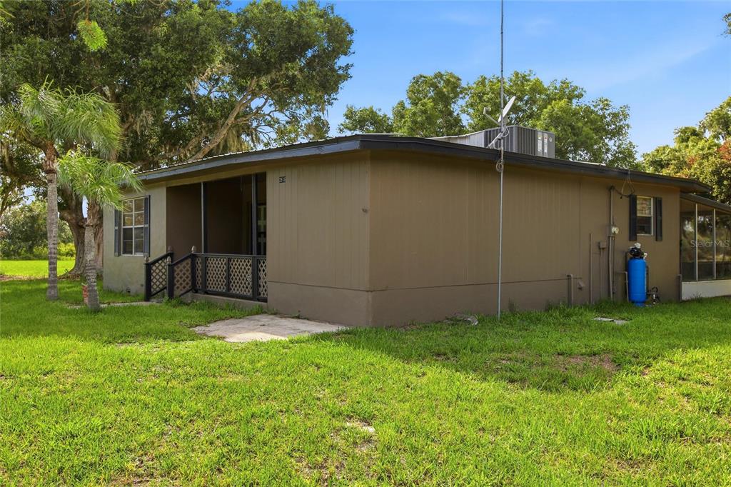 The exterior of a brown, single-story house features a screened porch and a grassy yard — 2616 HACIENDA DRIVE, LORIDA, FL