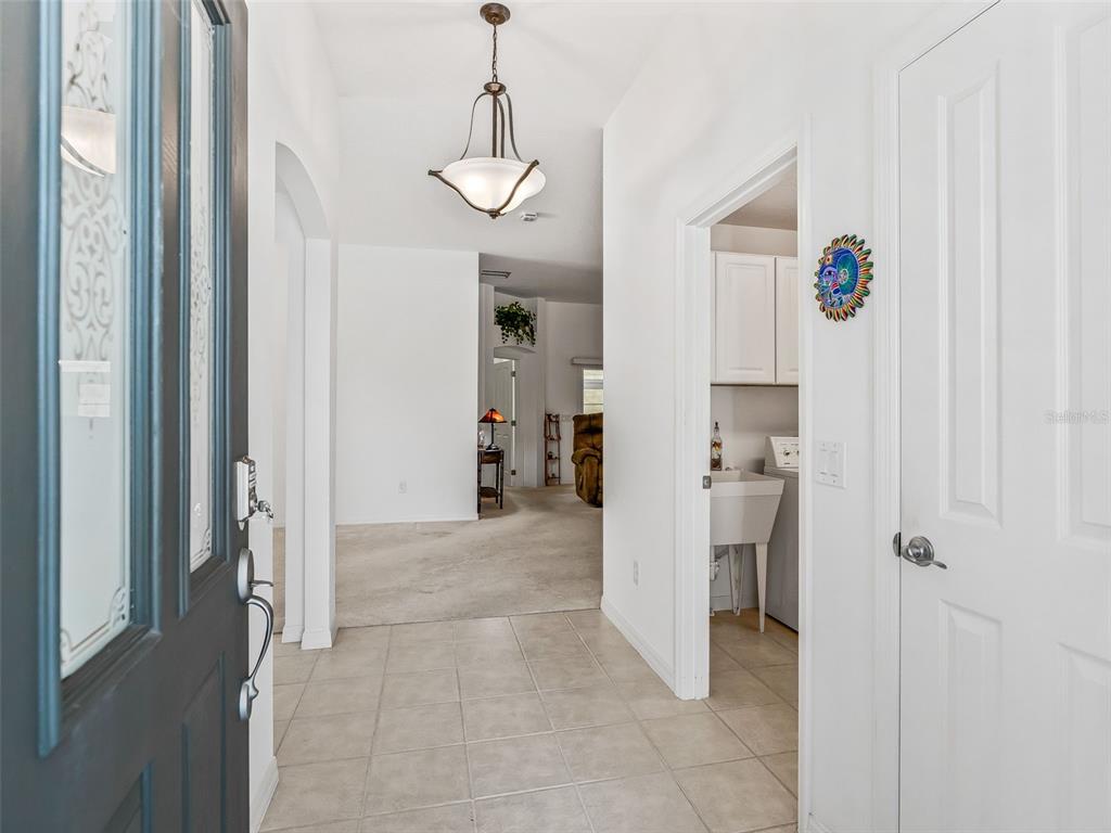 An entryway with tile flooring leads to a carpeted living area and a laundry room — 764 BAISLEY TRAIL, THE VILLAGES, FL