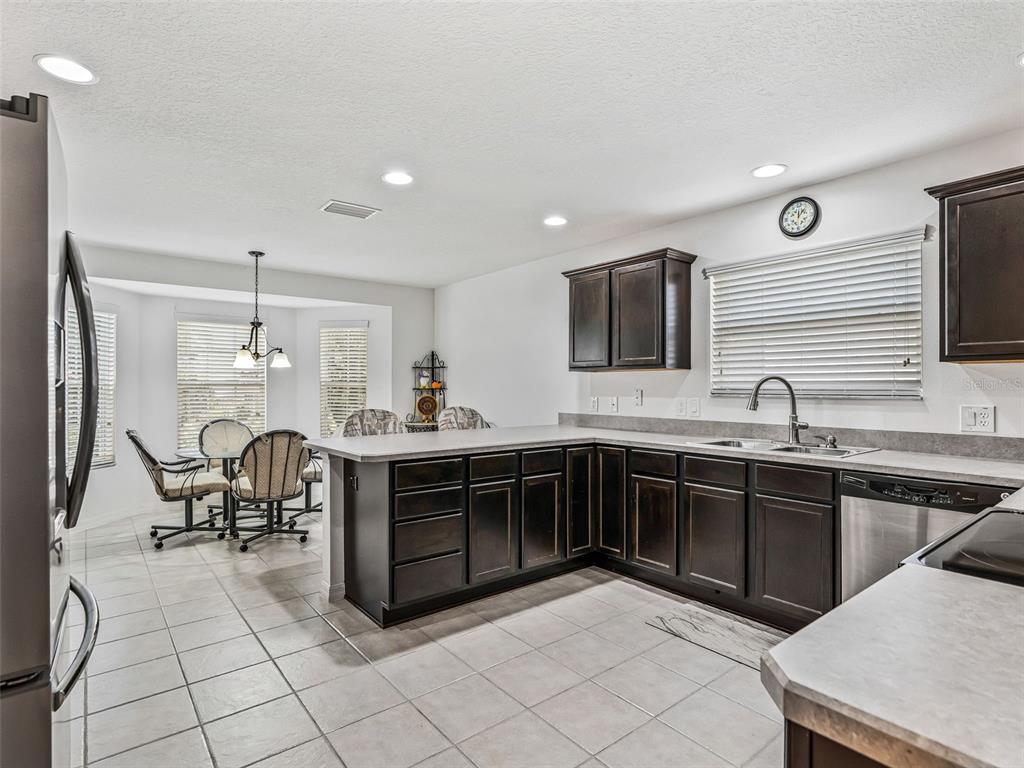 A kitchen with dark wood cabinets, a breakfast nook, and light-colored tile flooring — 764 BAISLEY TRAIL, THE VILLAGES, FL
