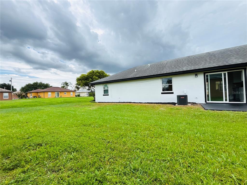 A white detached garage with two black doors sits on a concrete driveway — 504 BLACKBIRD LANE, POINCIANA, FL