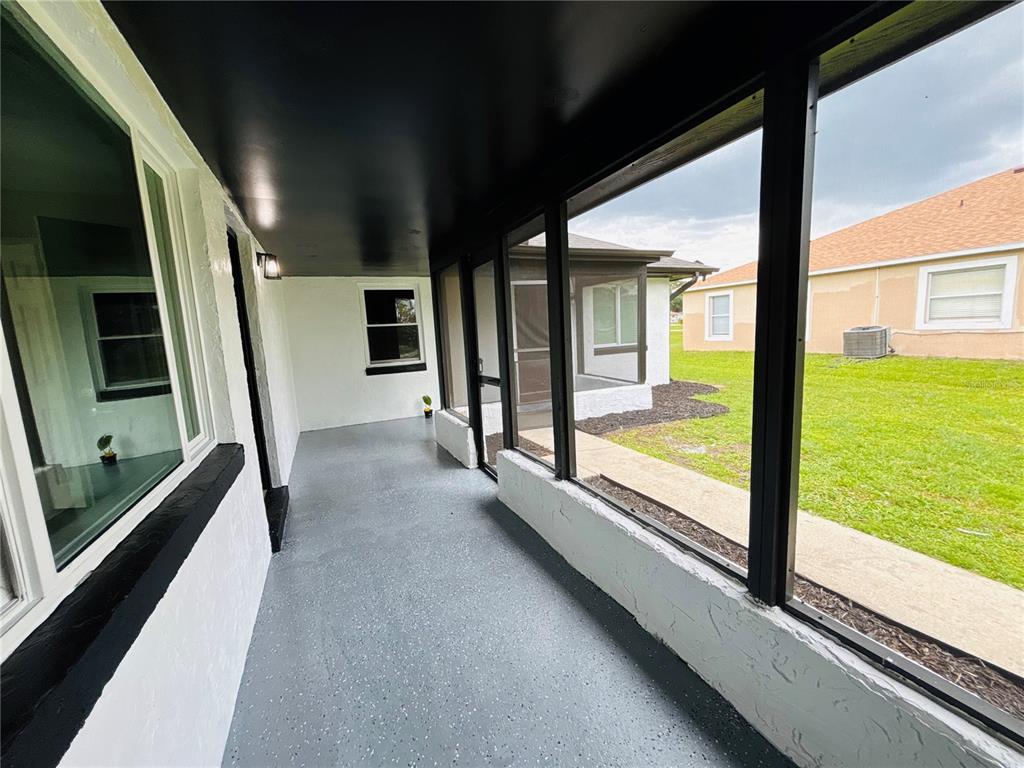 The exterior of a white concrete block house features a black patio and sliding doors — 504 BLACKBIRD LANE, POINCIANA, FL