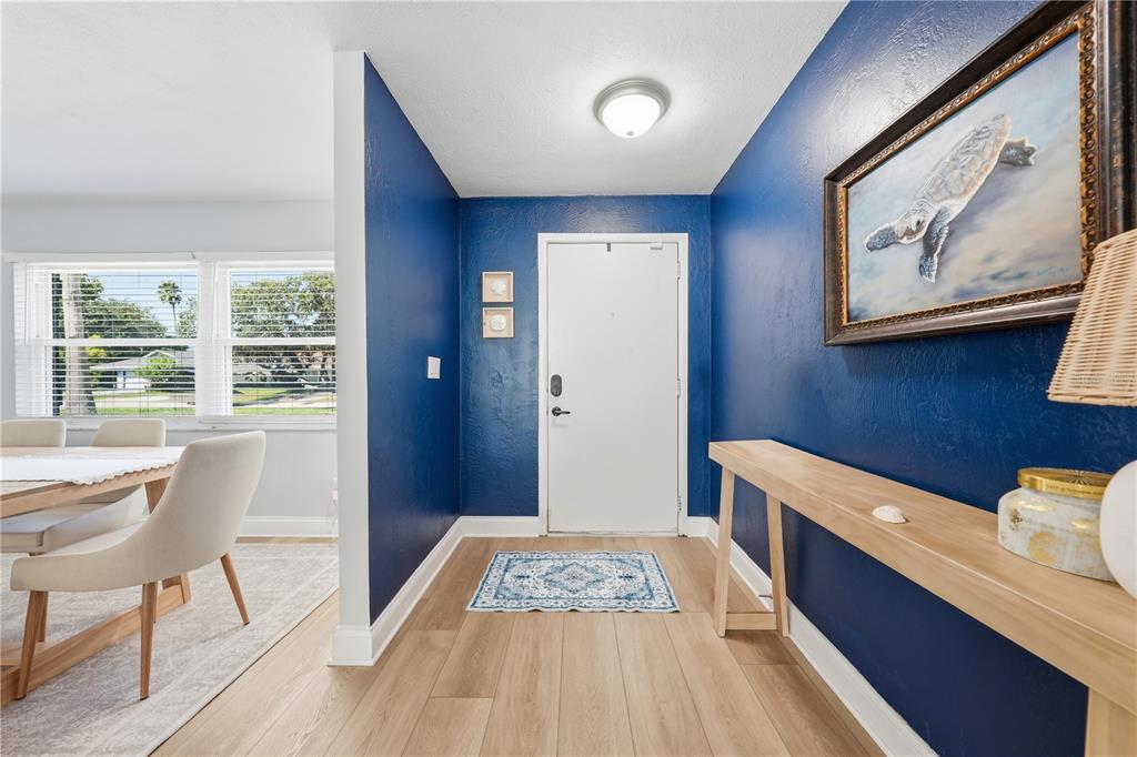 An entryway with blue walls, a white door, light wood flooring, and a console table — 636 DEVON STREET, PORT ORANGE, FL