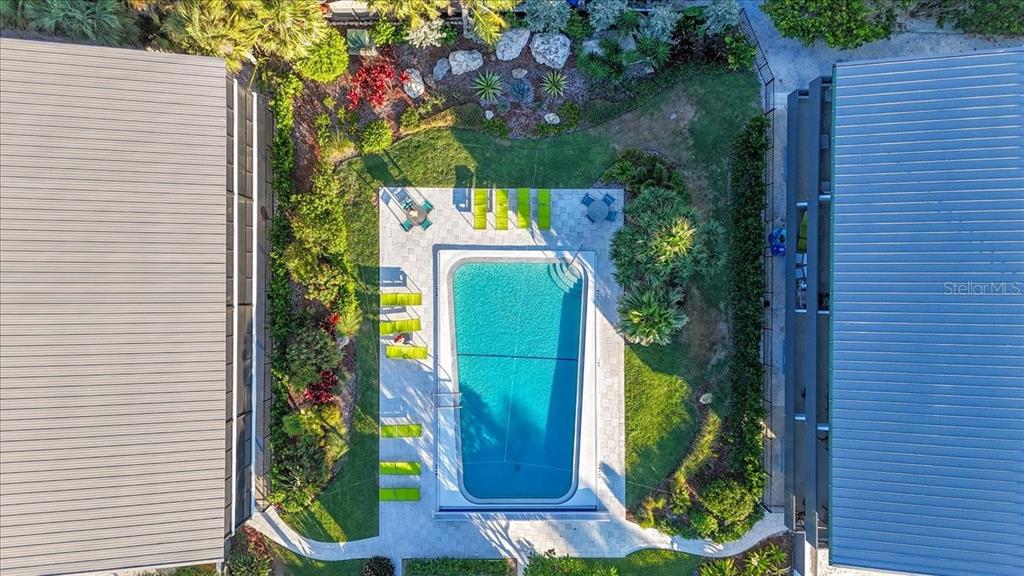 An aerial view shows a rectangular swimming pool situated between two buildings with metal roofs — 6804 GULF DRIVE UNIT 6804, HOLMES BEACH, FL