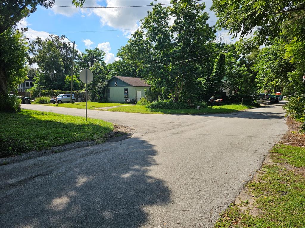 A street view of a residential intersection featuring a small green house and trees — 1906 VINE STREET, ORLANDO, FL