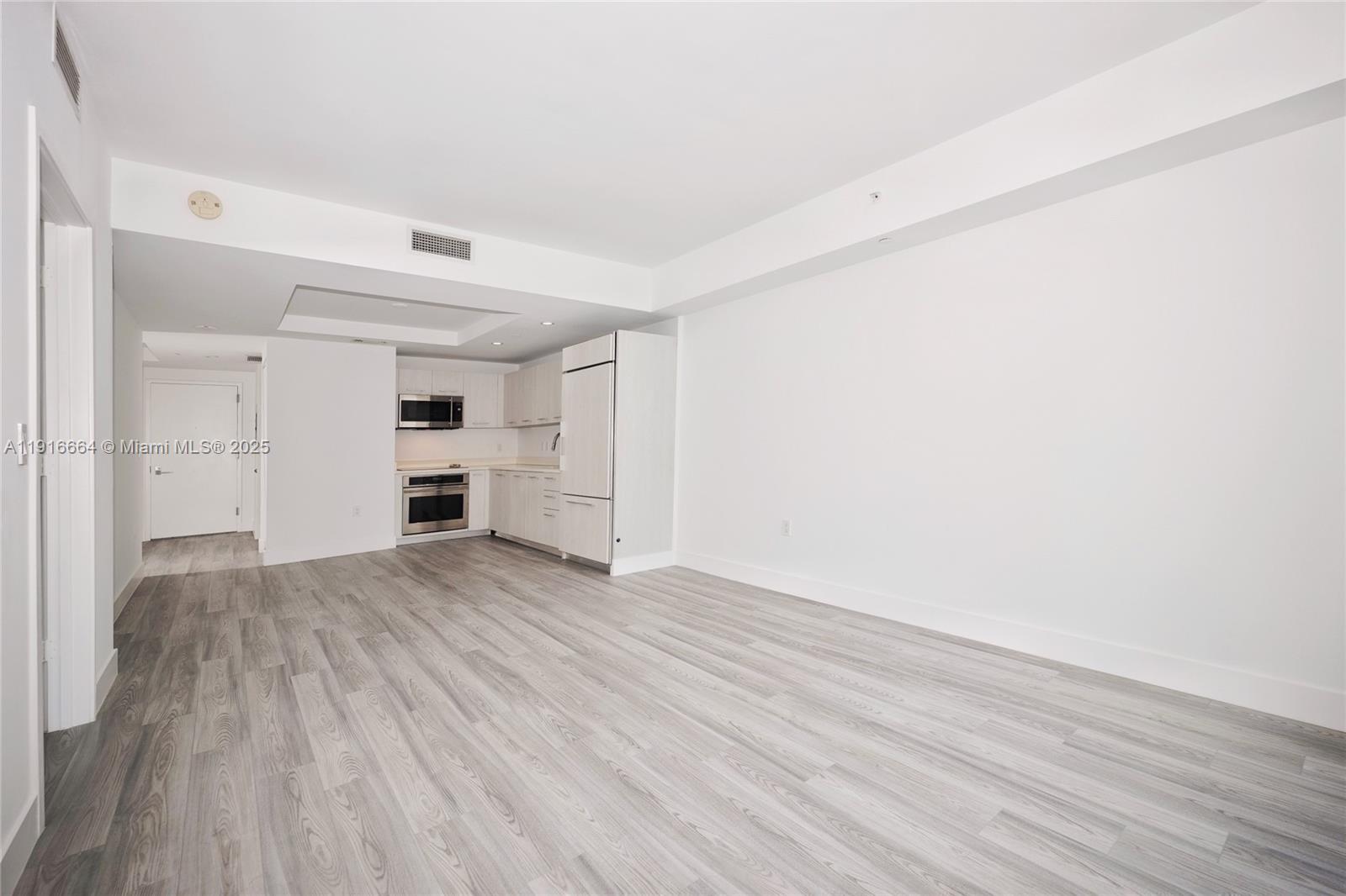 An open-concept kitchen and living area features white cabinetry, stainless steel appliances, and wood-look flooring — 45 SW 9th St # 1504, Miami FL 33130, MIAMI, FL