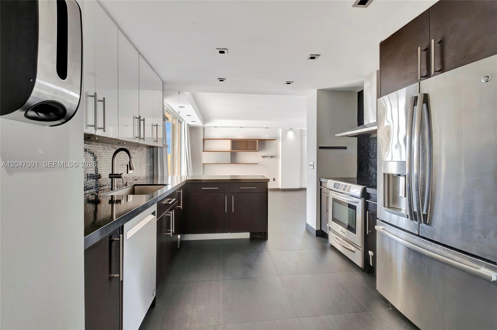 A modern kitchen features dark wood lower cabinets, white upper cabinets, and stainless steel appliances — 11111 Biscayne Blvd, Miami FL 33181, MIAMI, FL