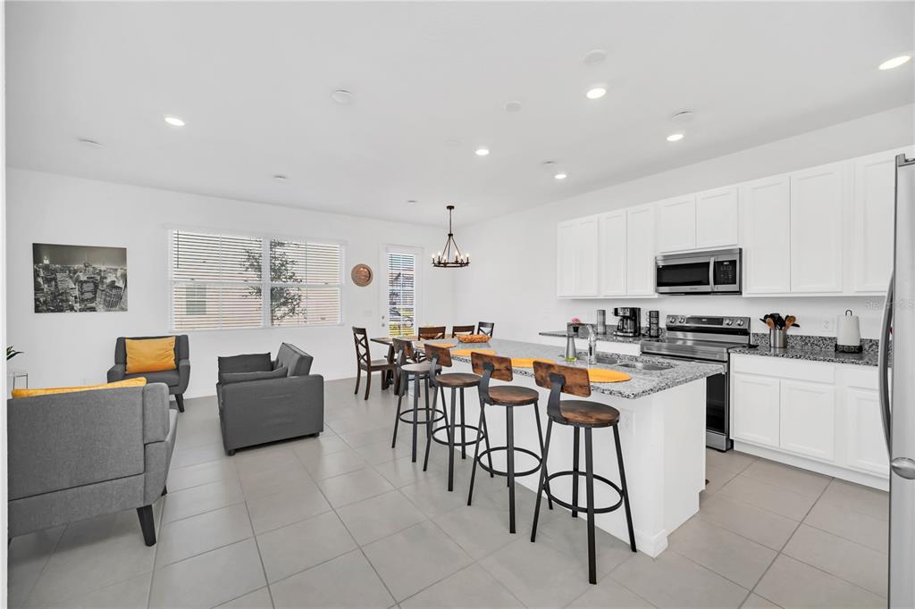 An open-concept kitchen and living area featuring white cabinets, granite countertops, and tile flooring — 808 LONGBOAT DRIVE, DAVENPORT, FL
