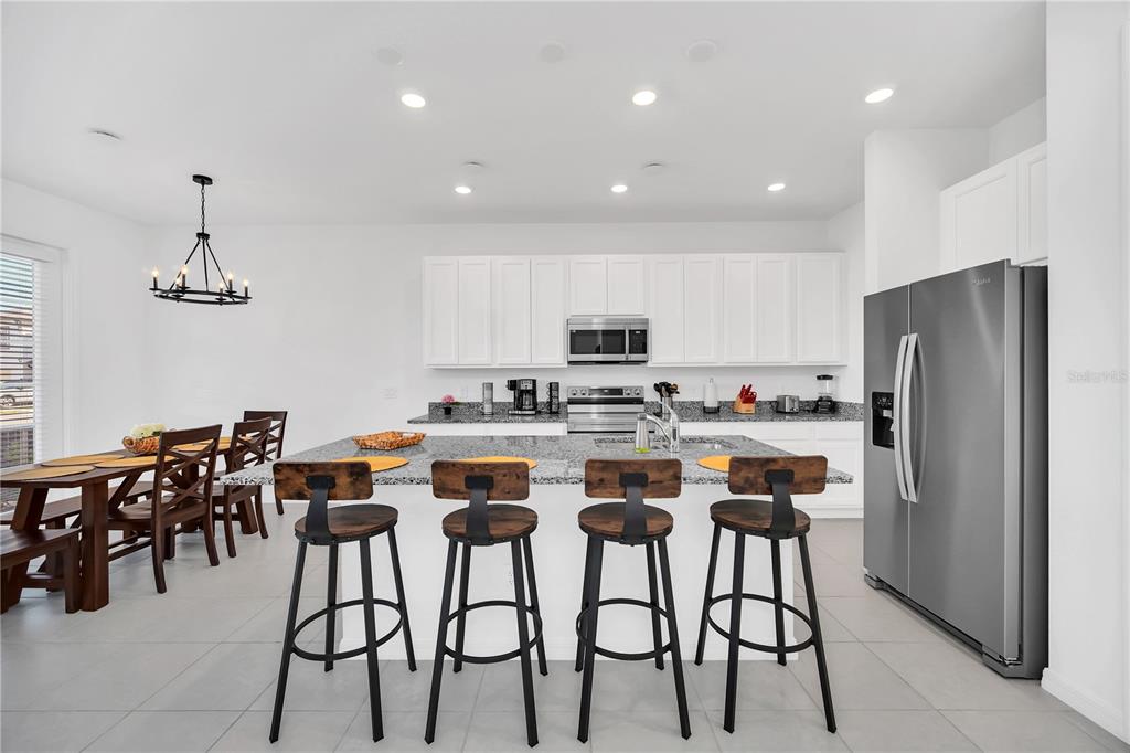 A kitchen with white cabinets, granite countertops, a center island with bar stools, and appliances — 808 LONGBOAT DRIVE, DAVENPORT, FL