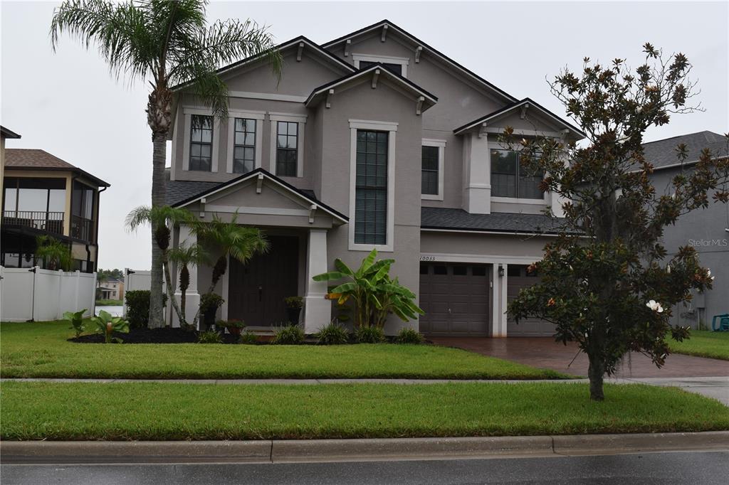 A two-story suburban house with a gray exterior, a two-car garage, and a palm tree — 10033 LAKE DISTRICT LANE, ORLANDO, FL