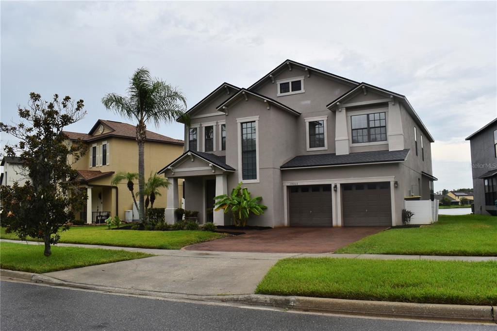 A two-story gray house with a two-car garage and a palm tree in the yard — 10033 LAKE DISTRICT LANE, ORLANDO, FL