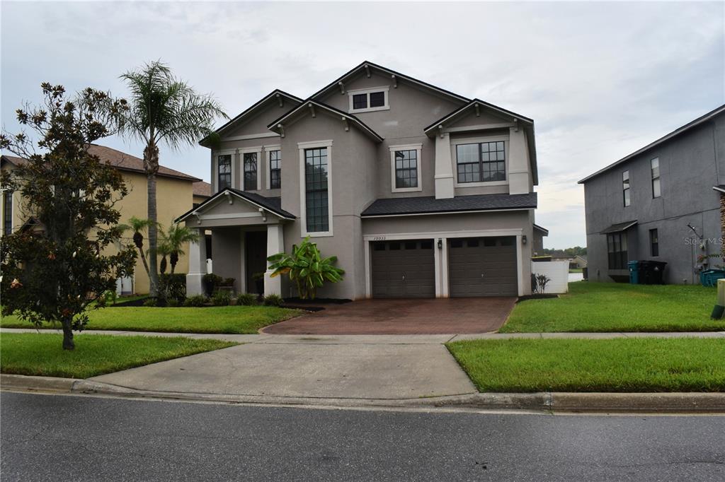 A two-story suburban house with a gray stucco exterior, a two-car garage, and a driveway — 10033 LAKE DISTRICT LANE, ORLANDO, FL