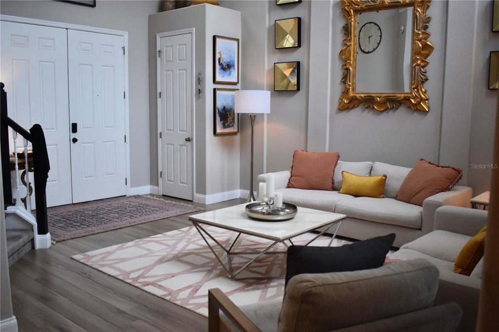 A living room features a white sofa, a geometric coffee table, and a large gold mirror — 10033 LAKE DISTRICT LANE, ORLANDO, FL