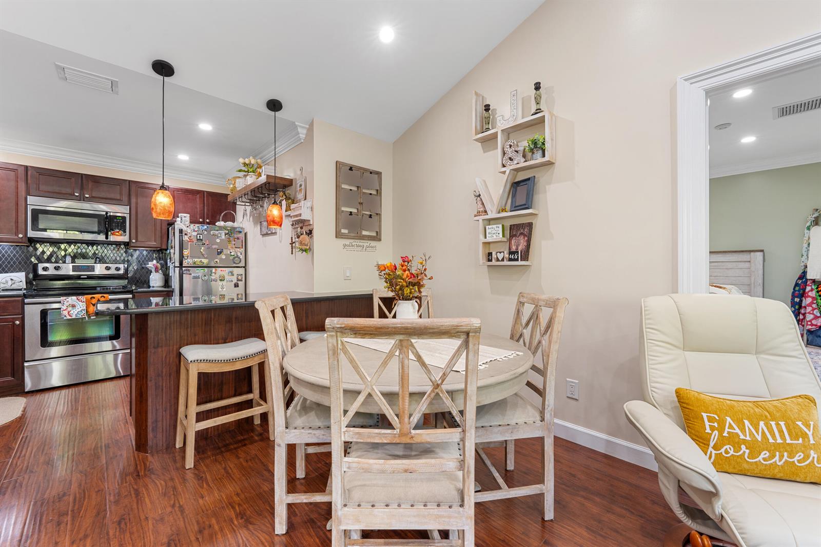 A dining area with a round table and chairs sits adjacent to a kitchen with dark cabinets — 1616 SE Green Acres Circle # M204, FL 34952, FL