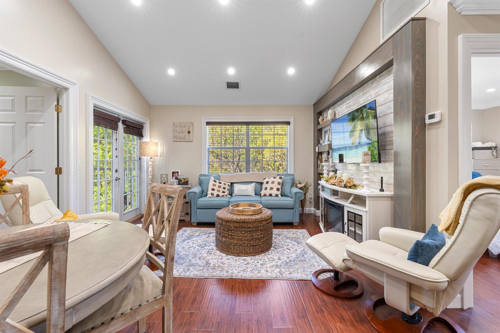 A living room features a blue sofa, a round woven ottoman, and a wall-mounted television — 1616 SE Green Acres Circle # M204, FL 34952, FL