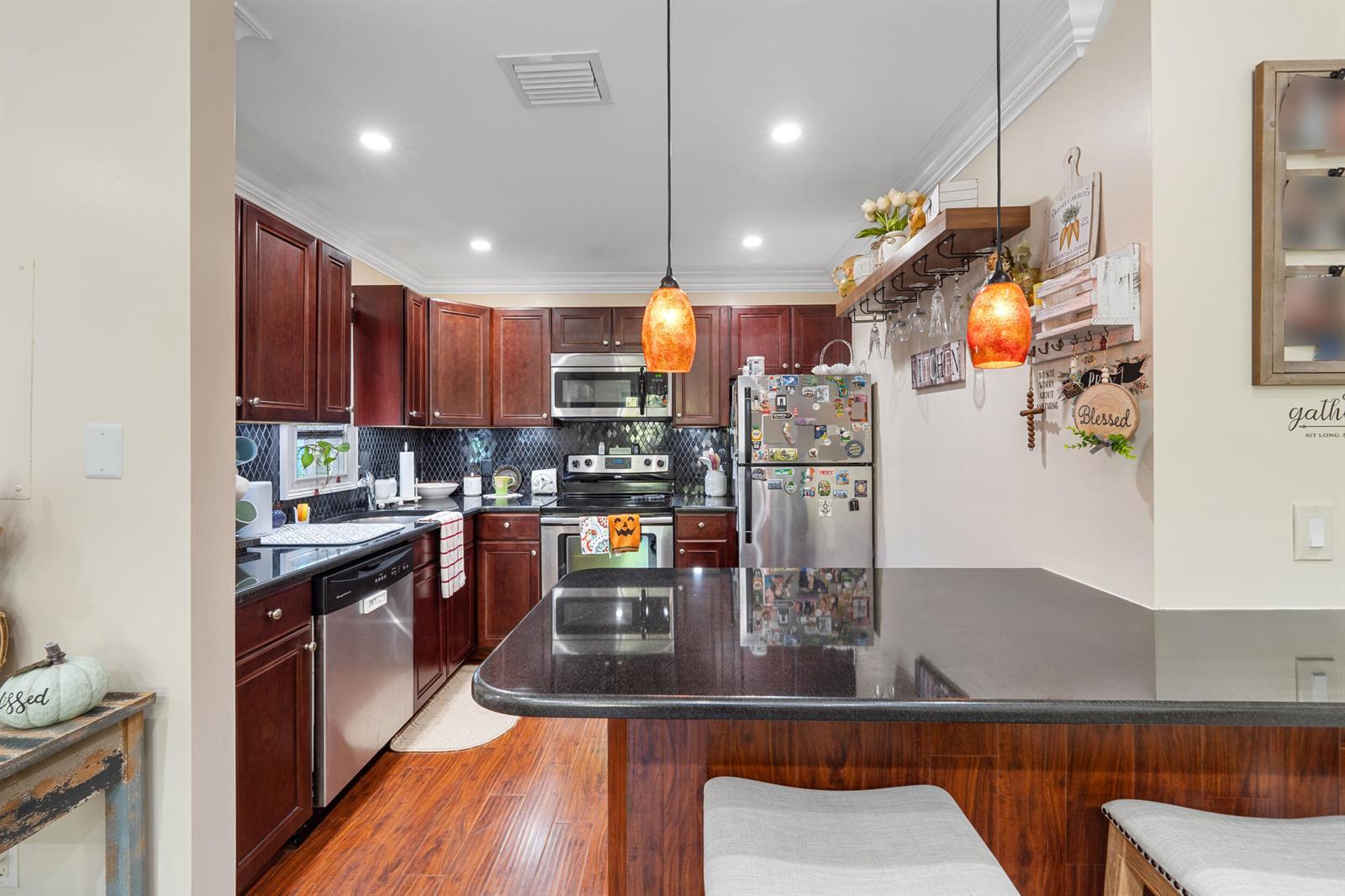 A kitchen features dark wood cabinets, black granite countertops, stainless steel appliances, and pendant lighting — 1616 SE Green Acres Circle # M204, FL 34952, FL