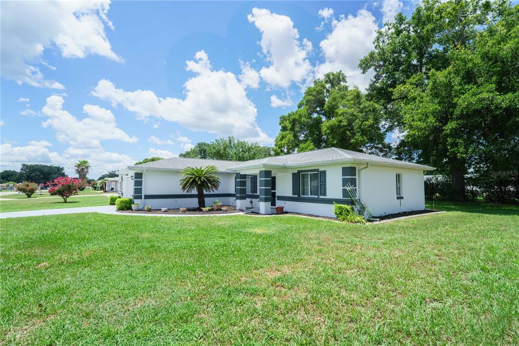 A white house with a two-car garage and a large green lawn under a blue sky — 10280 SW 62ND TERRACE ROAD, OCALA, FL
