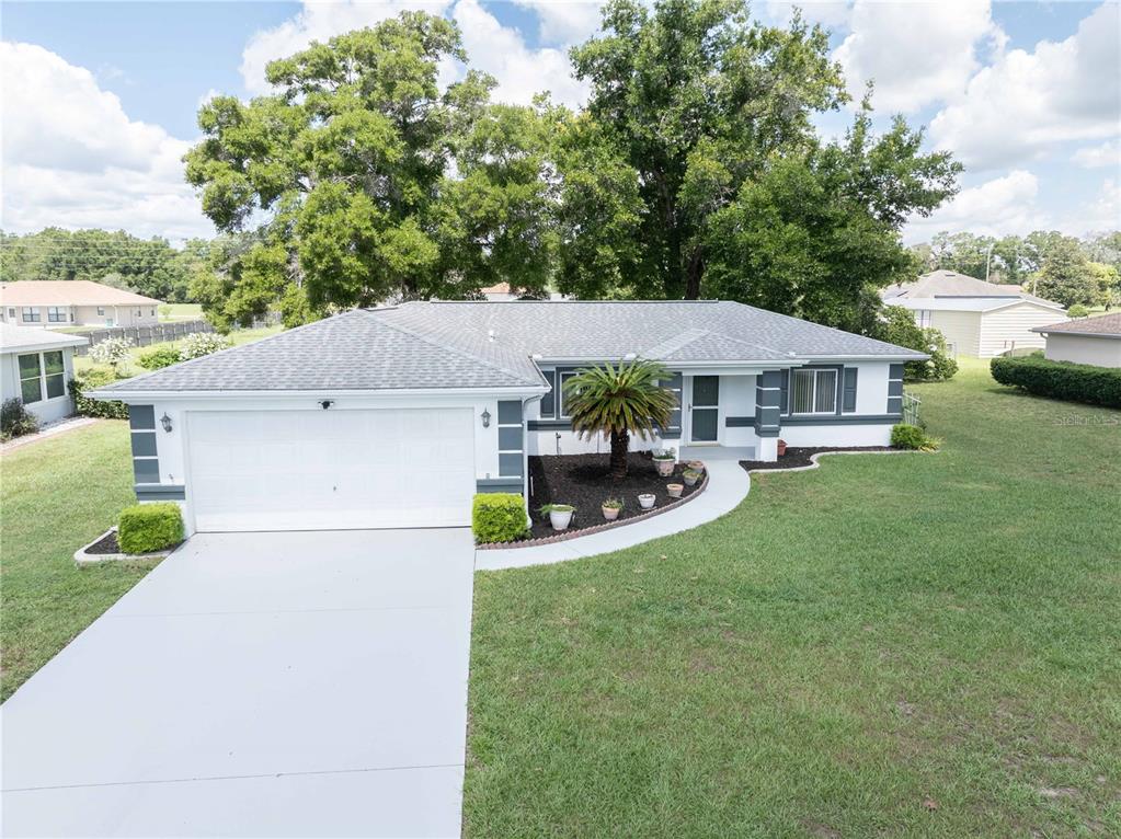 A white single-story house with a grey roof and dark shutters sits on a lawn — 10280 SW 62ND TERRACE ROAD, OCALA, FL