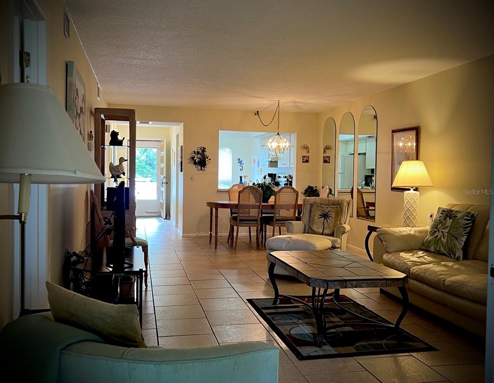 A living room and dining area with tile floors, a coffee table, and arched mirrors — 4499 LONGMEADOW UNIT 79, SARASOTA, FL
