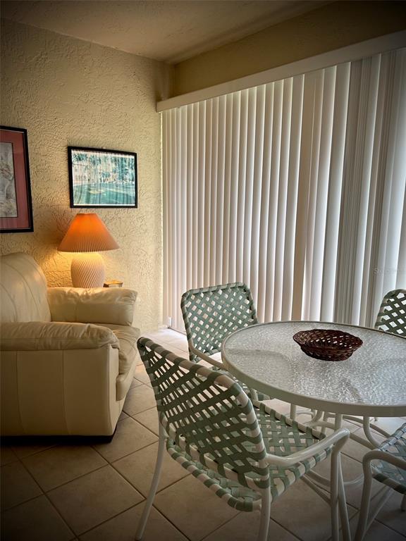 A room features a beige sofa, a lamp, a glass-topped table, and woven chairs — 4499 LONGMEADOW UNIT 79, SARASOTA, FL