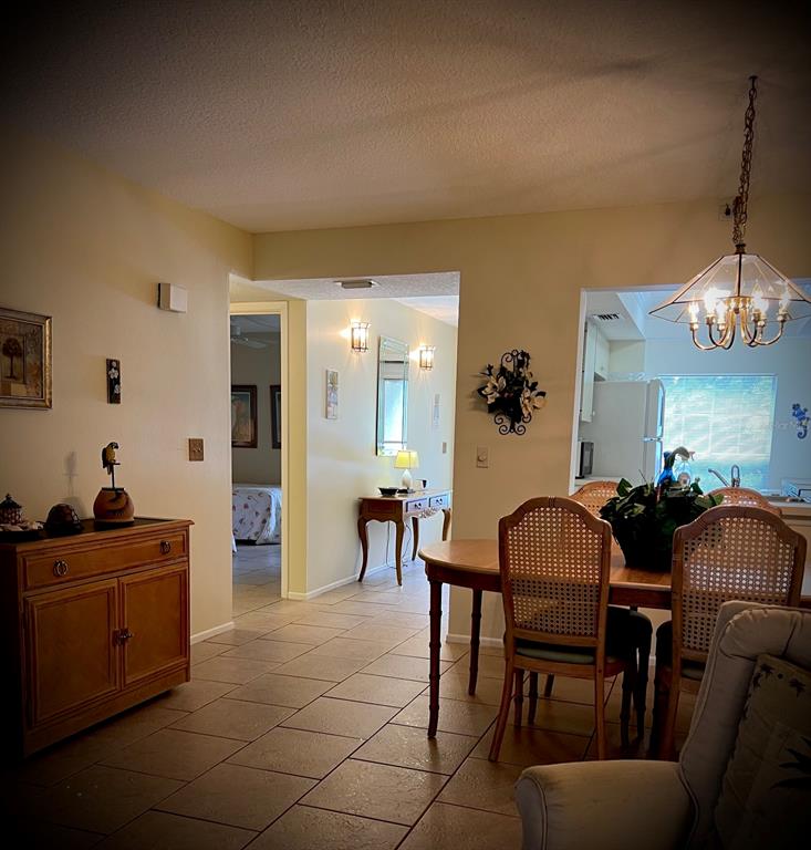 A dining area with a wooden table and chairs leads to a hallway and kitchen — 4499 LONGMEADOW UNIT 79, SARASOTA, FL