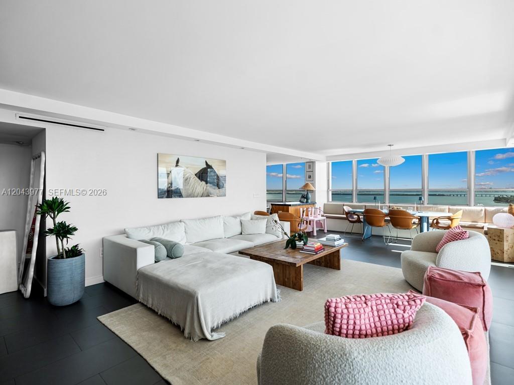 A living room with a white sectional, wooden coffee table, and floor-to-ceiling windows overlooking water — 11 Island Ave # 1712, Miami Beach FL 33139, MIAMI BEACH, FL