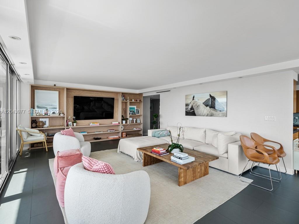 A modern living room features a large sectional sofa, two white armchairs, and built-in shelving — 11 Island Ave # 1712, Miami Beach FL 33139, MIAMI BEACH, FL