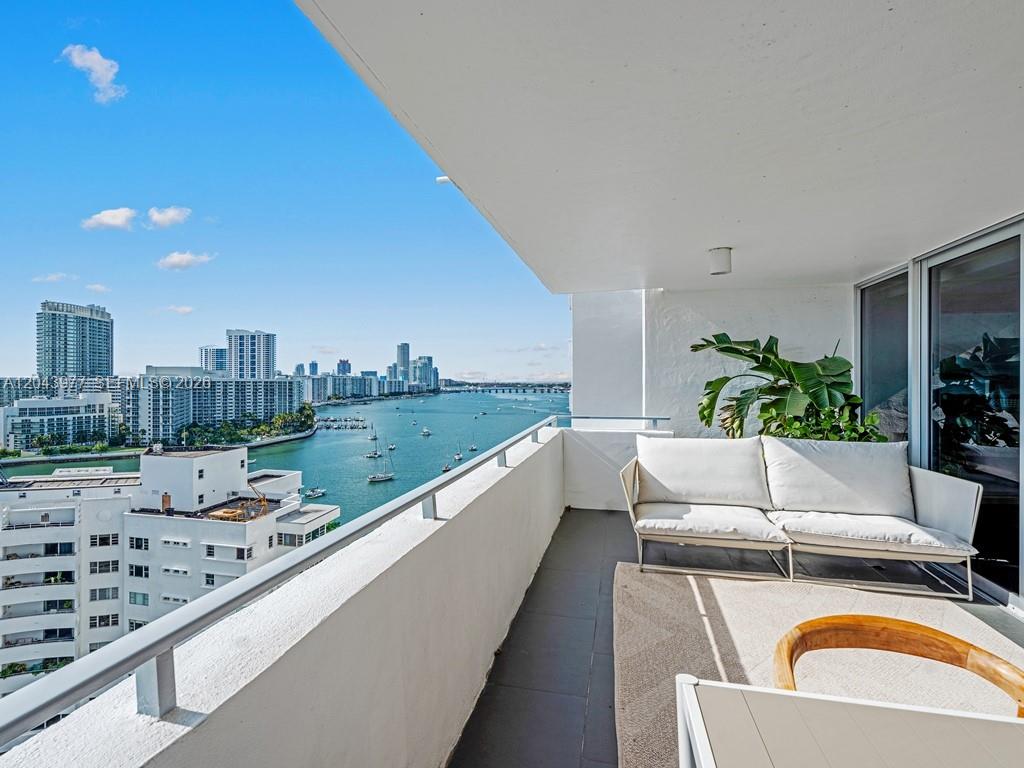 A balcony with a white sofa overlooks a bay and a city skyline — 11 Island Ave # 1712, Miami Beach FL 33139, MIAMI BEACH, FL