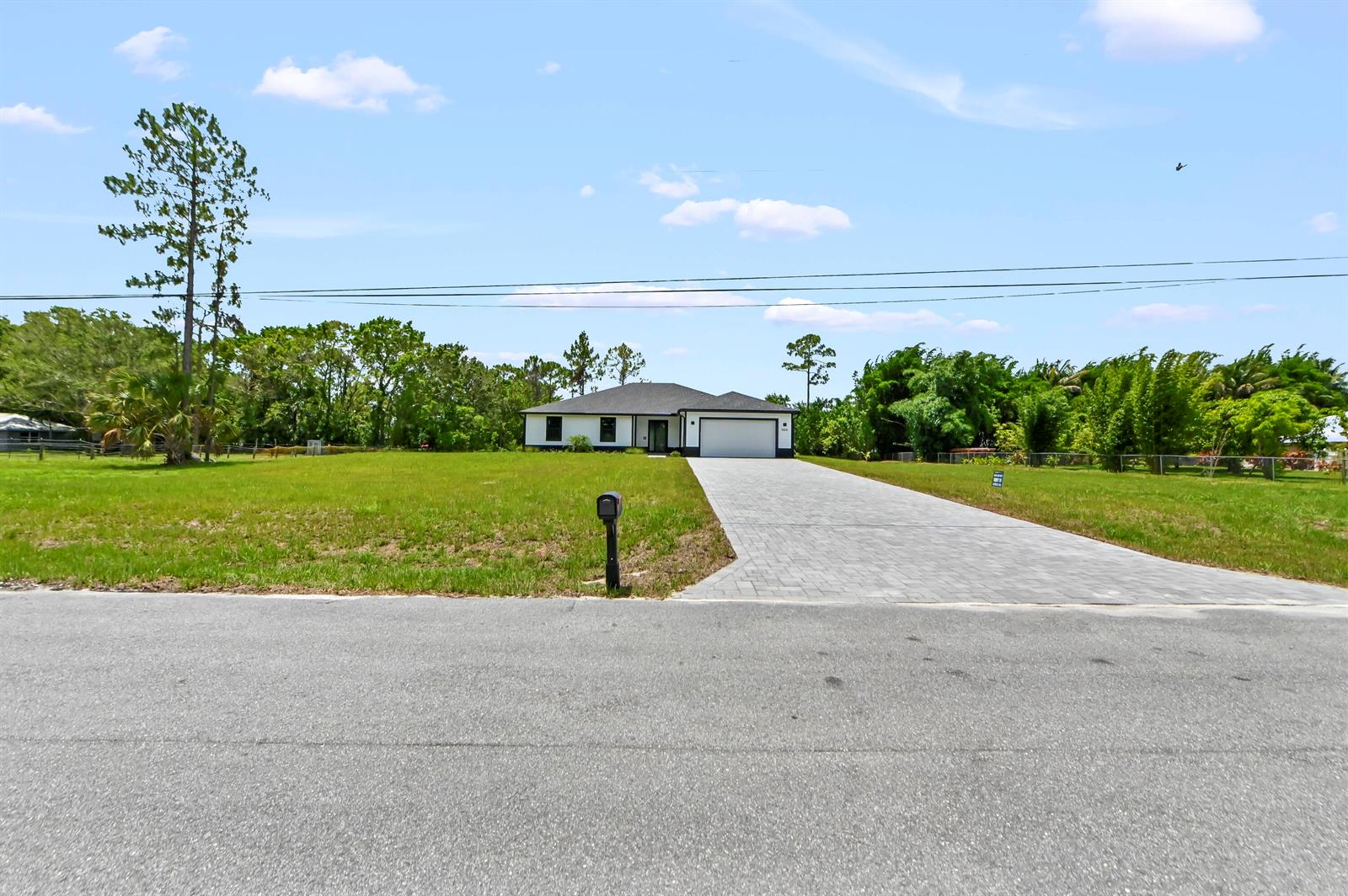 A single-story house with a paved driveway sits on a large, grassy lot — 14826 89th Place N, Loxahatchee FL 33470, LOXAHATCHEE, FL