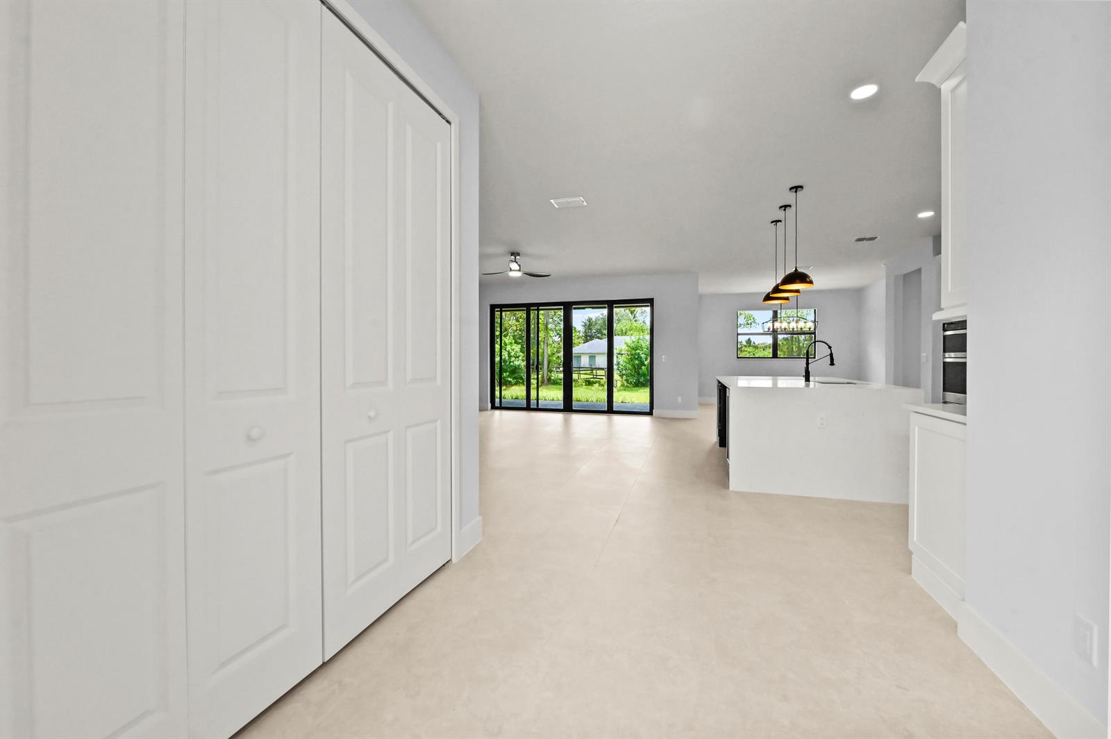 A bright, open-concept kitchen and living area features white cabinetry, a kitchen island, and tile — 14826 89th Place N, Loxahatchee FL 33470, LOXAHATCHEE, FL