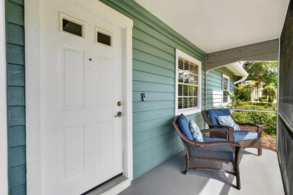 A covered porch features green siding, a white front door, and two wicker chairs — 46 WOOD CEDAR DRIVE, PALM COAST, FL