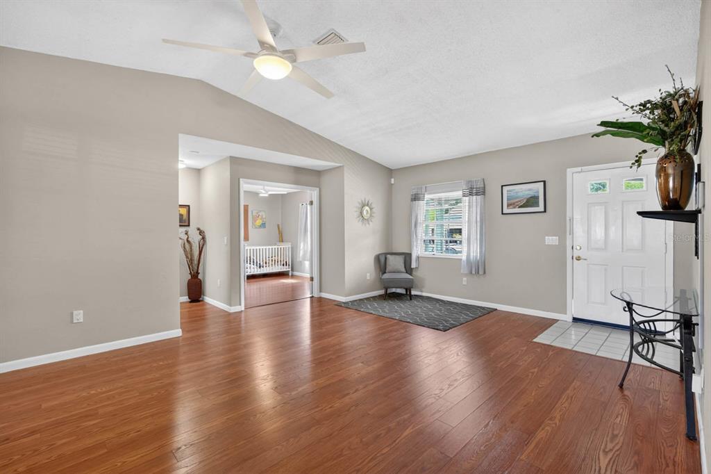 A living room with wood-look flooring, a vaulted ceiling, a ceiling fan, and an entryway — 46 WOOD CEDAR DRIVE, PALM COAST, FL