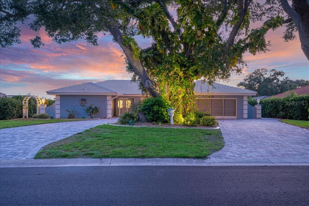 A single-story house with a paved driveway and a large tree in the front yard — 413 SIGNORELLI DRIVE, NOKOMIS, FL