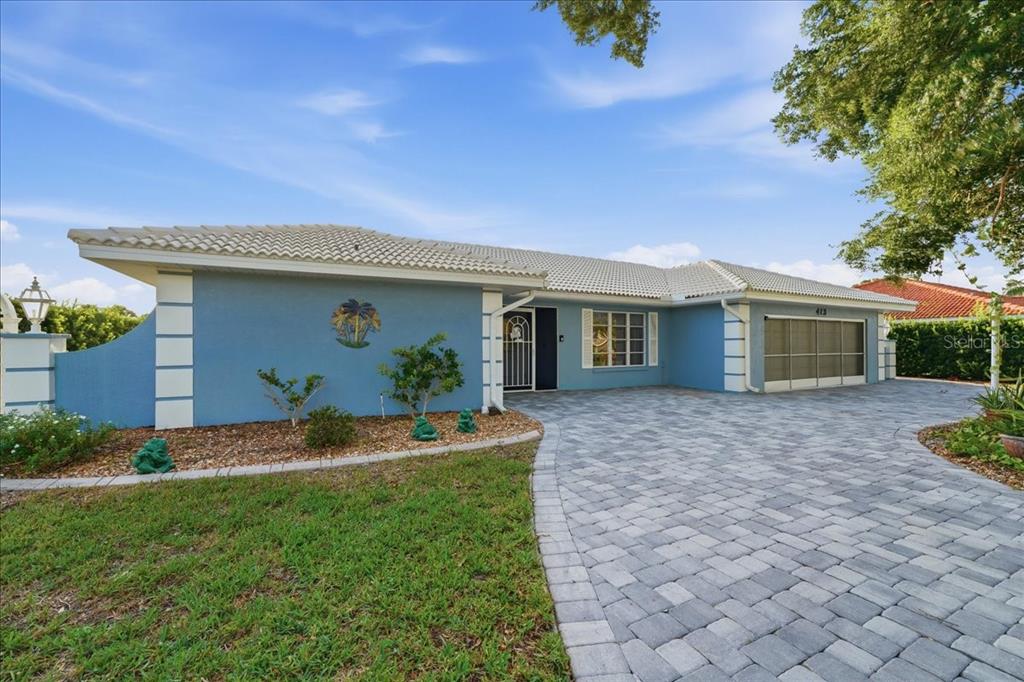A blue single-story house features a tiled roof, a paved driveway, and a two-car garage — 413 SIGNORELLI DRIVE, NOKOMIS, FL
