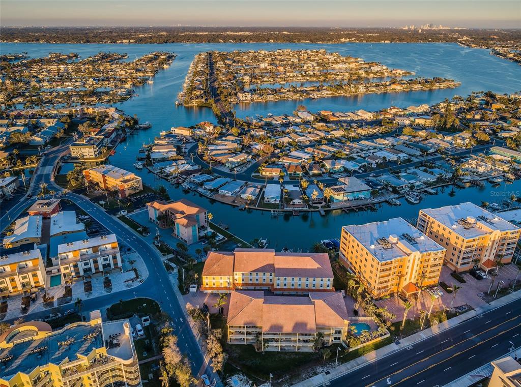 An aerial view shows a multi-story apartment complex surrounded by residential canals and coastal waterways — 11595 GULF BOULEVARD UNIT 6, TREASURE ISLAND, FL