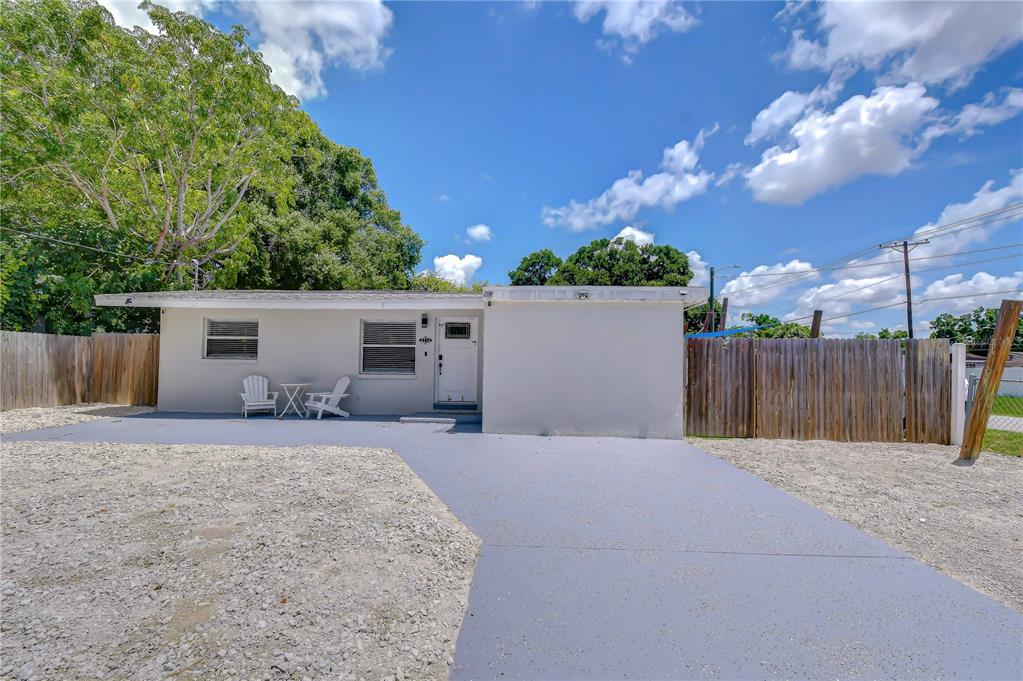 A single-story house with a white exterior, a gray concrete patio, and a gravel yard — 2714 E 98TH AVENUE, TAMPA, FL