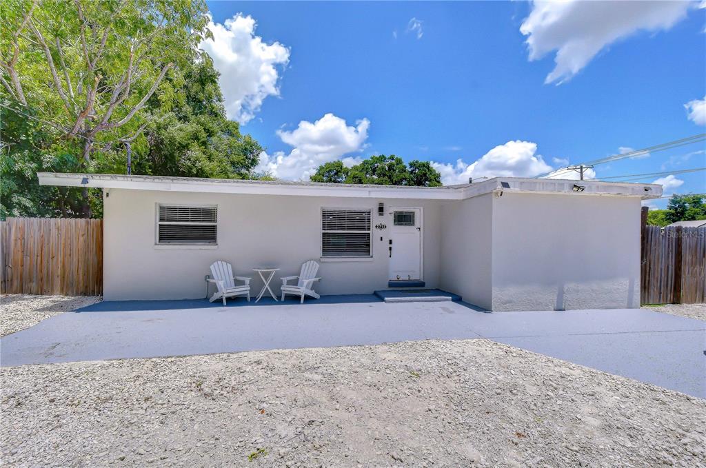 A single-story house with a painted concrete patio, white door, and two Adirondack chairs — 2714 E 98TH AVENUE, TAMPA, FL