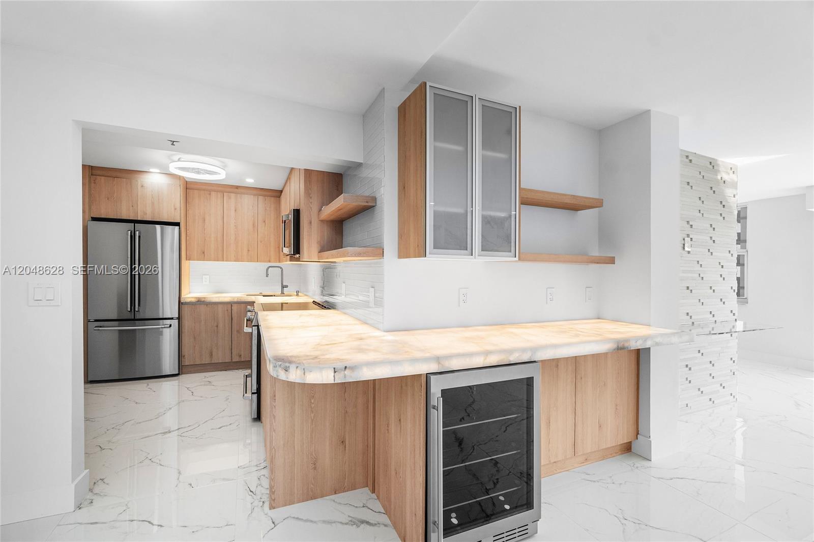 A modern kitchen features light wood cabinetry, white marble floors, and a backlit stone countertop — 4505 S Ocean Blvd # 703, Highland Beach FL 33487, HIGHLAND BEACH, FL