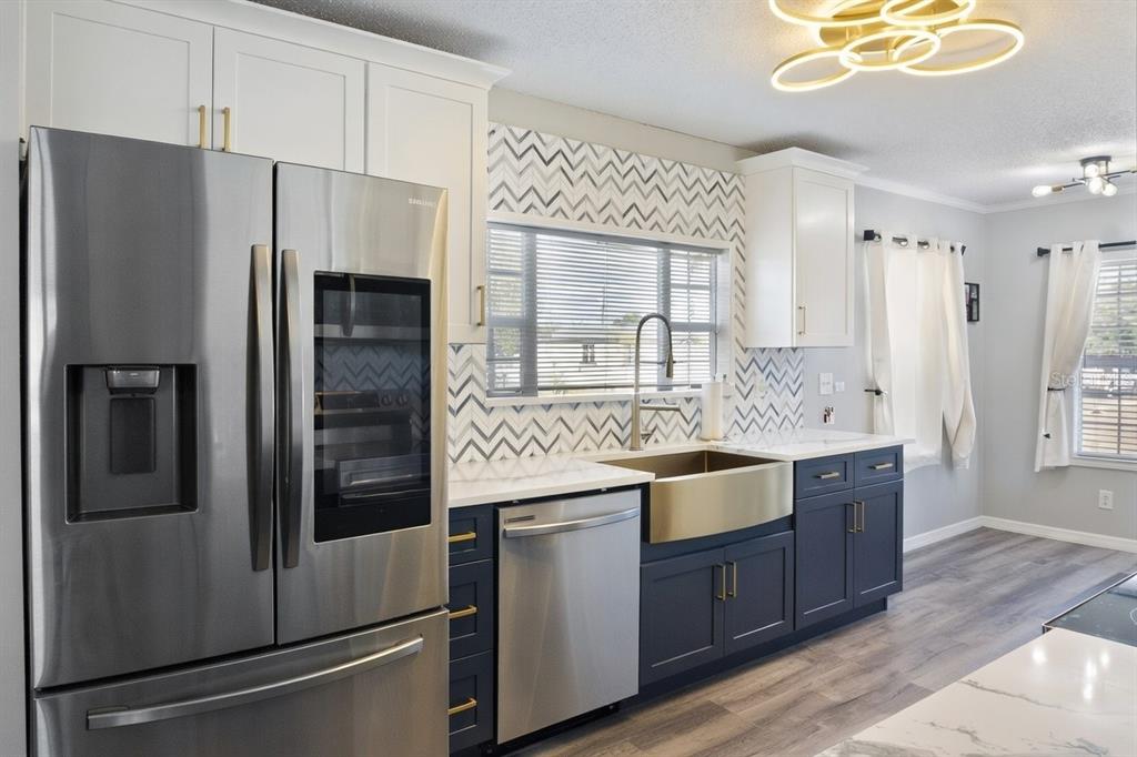 A kitchen features dark blue lower cabinets, white upper cabinets, and a gold farmhouse sink — 6533 JACK STREET, PUNTA GORDA, FL