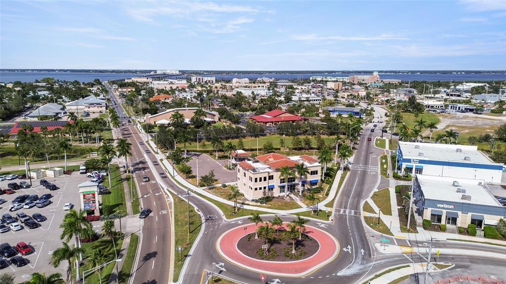 An aerial view shows a roundabout, commercial buildings, parking lots, and a distant bridge — 6533 JACK STREET, PUNTA GORDA, FL