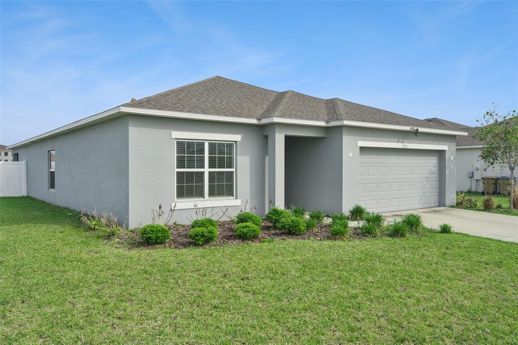 A single-story house with gray stucco siding, a shingled roof, and a two-car garage — 392 CITRINE LOOP, KISSIMMEE, FL