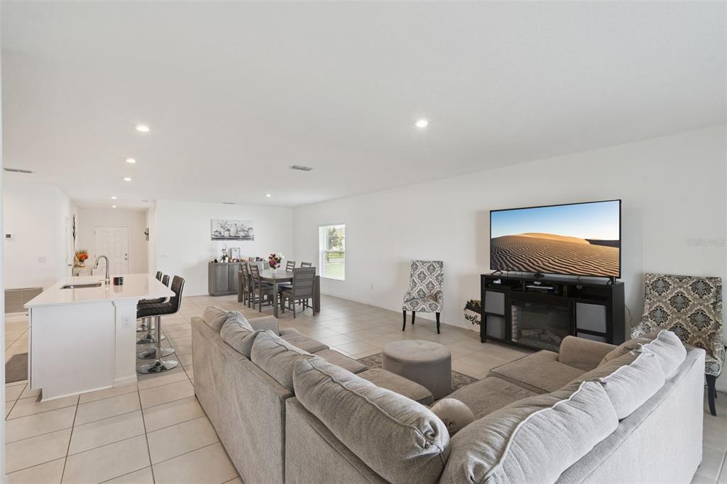 An open-concept living and dining area features a kitchen island, tile flooring, and neutral walls — 392 CITRINE LOOP, KISSIMMEE, FL