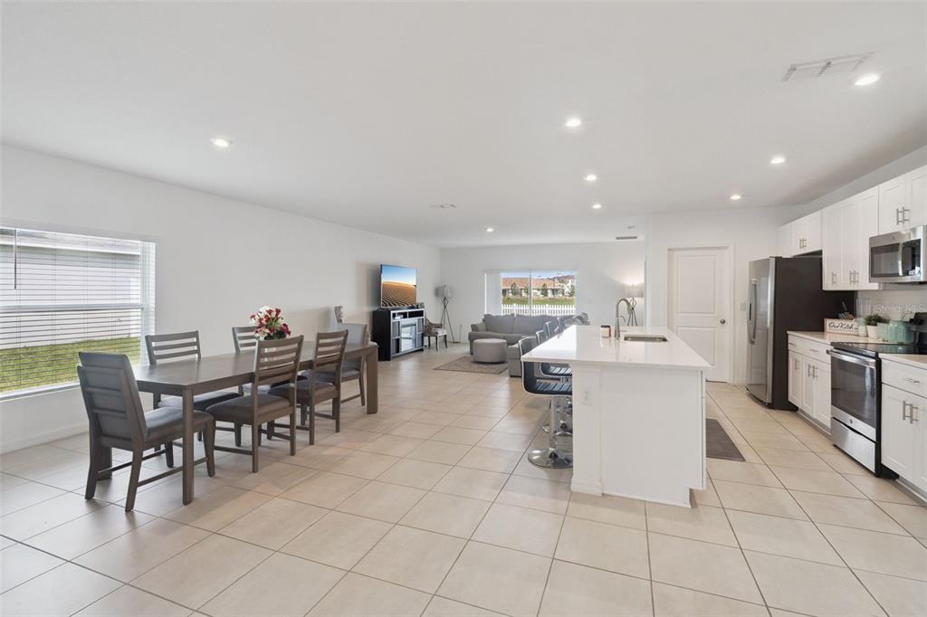 An open-concept kitchen and dining area features white cabinets, a central island, and tile flooring — 392 CITRINE LOOP, KISSIMMEE, FL