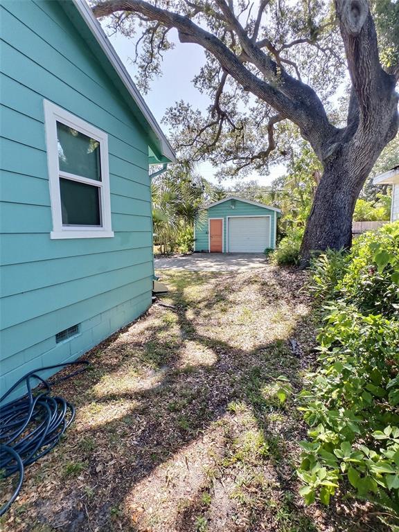 The exterior view shows a teal house, a detached garage, and a large tree — 1431 PALOMA LANE, DUNEDIN, FL