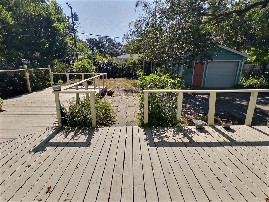 A wooden deck overlooks a backyard with a paved path and a detached garage — 1431 PALOMA LANE, DUNEDIN, FL