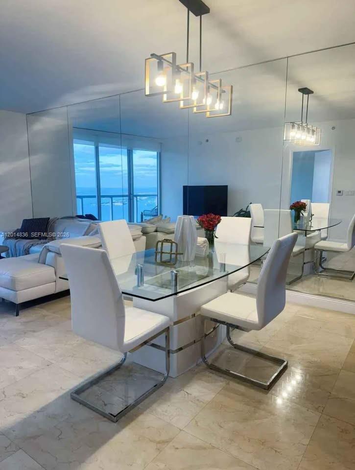 A dining area with a glass table, white chairs, and a large mirrored wall — 495 Brickell Ave # 4809, Miami FL 33131, MIAMI, FL