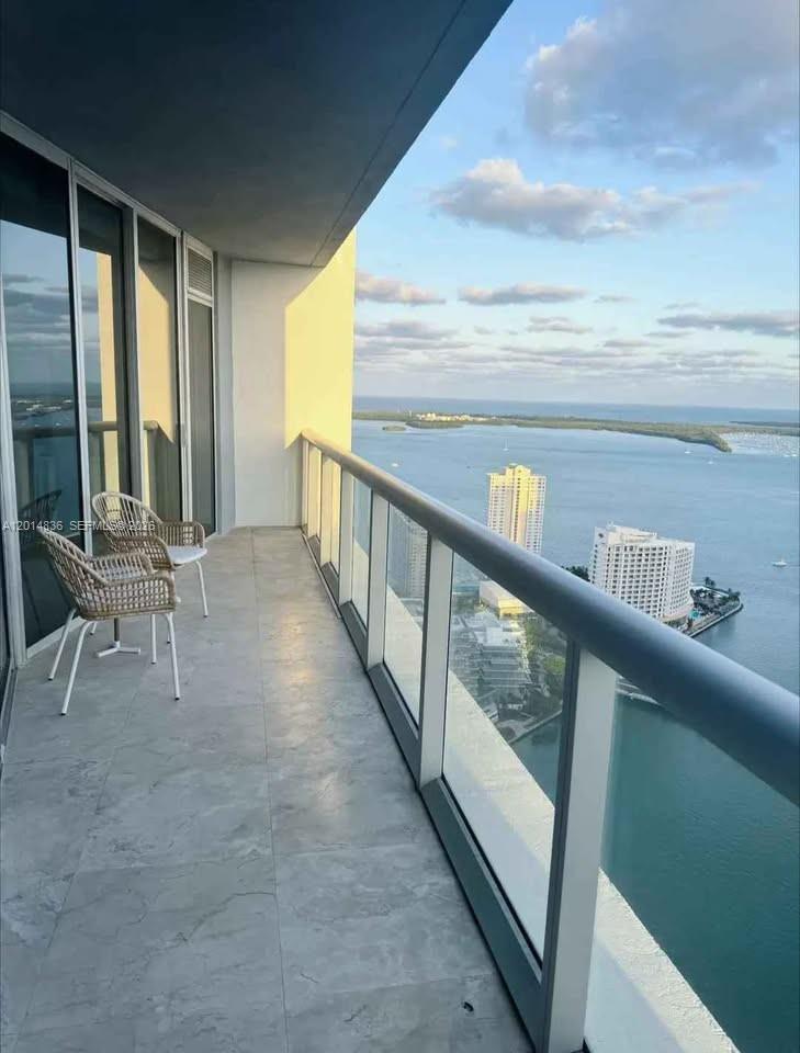 A high-rise balcony with two chairs overlooks a bay with buildings and water — 495 Brickell Ave # 4809, Miami FL 33131, MIAMI, FL
