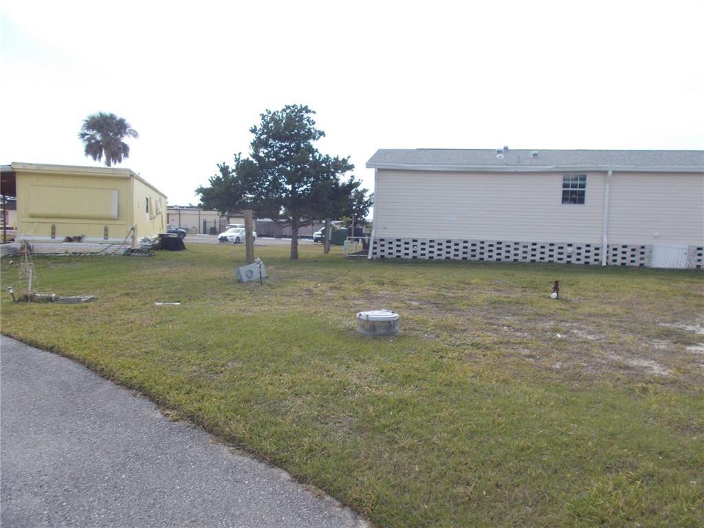 A grassy yard sits between a yellow mobile home and a beige manufactured home — 5501 HOLIDAY PARK BOULEVARD, NORTH PORT, FL