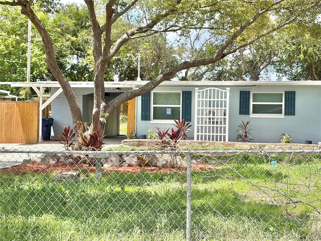 A single-story house with a light blue exterior, dark shutters, and a large tree out front — 12119 VICTORY DRIVE, HUDSON, FL
